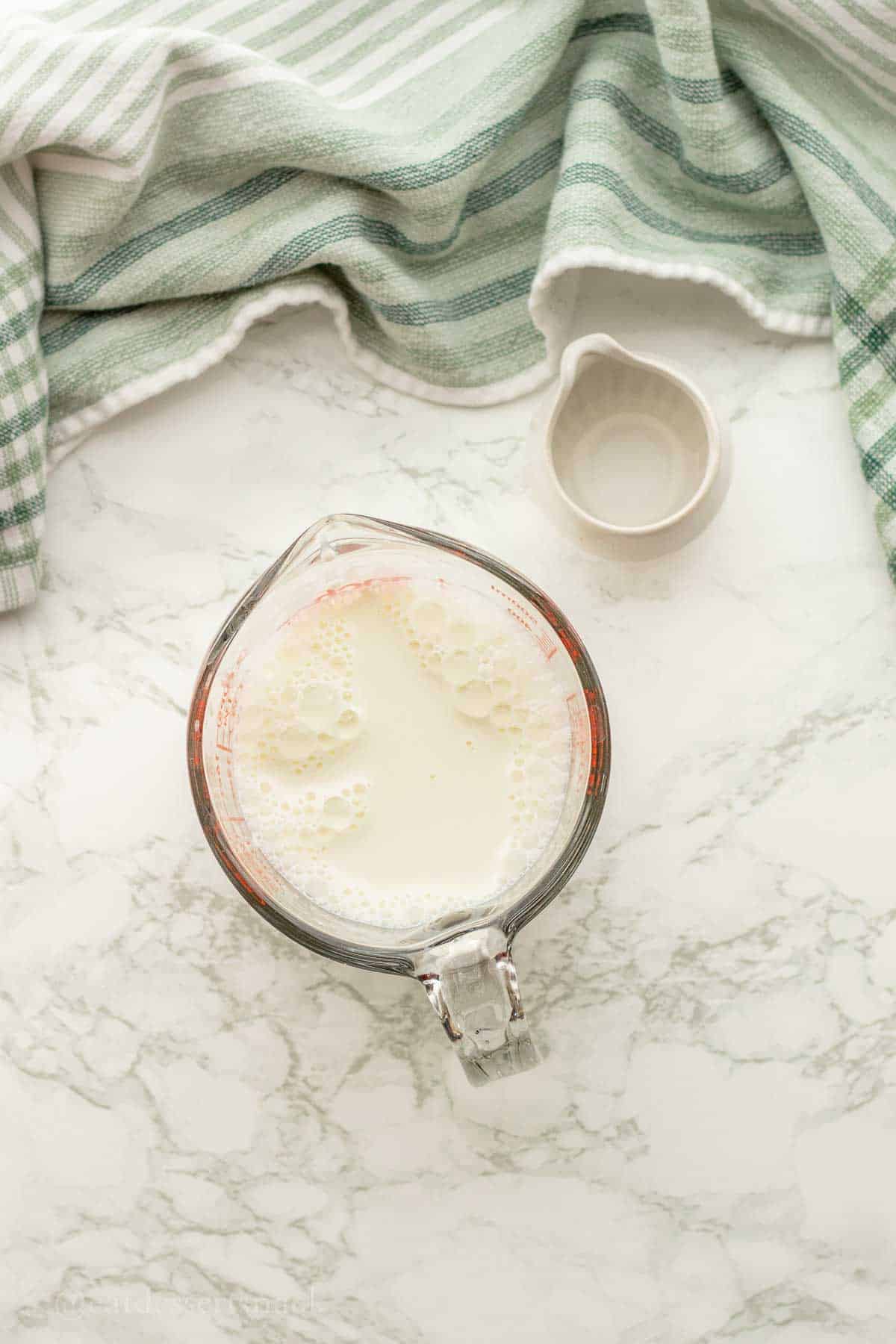 Milk and dish of vinegar on marble countertop.