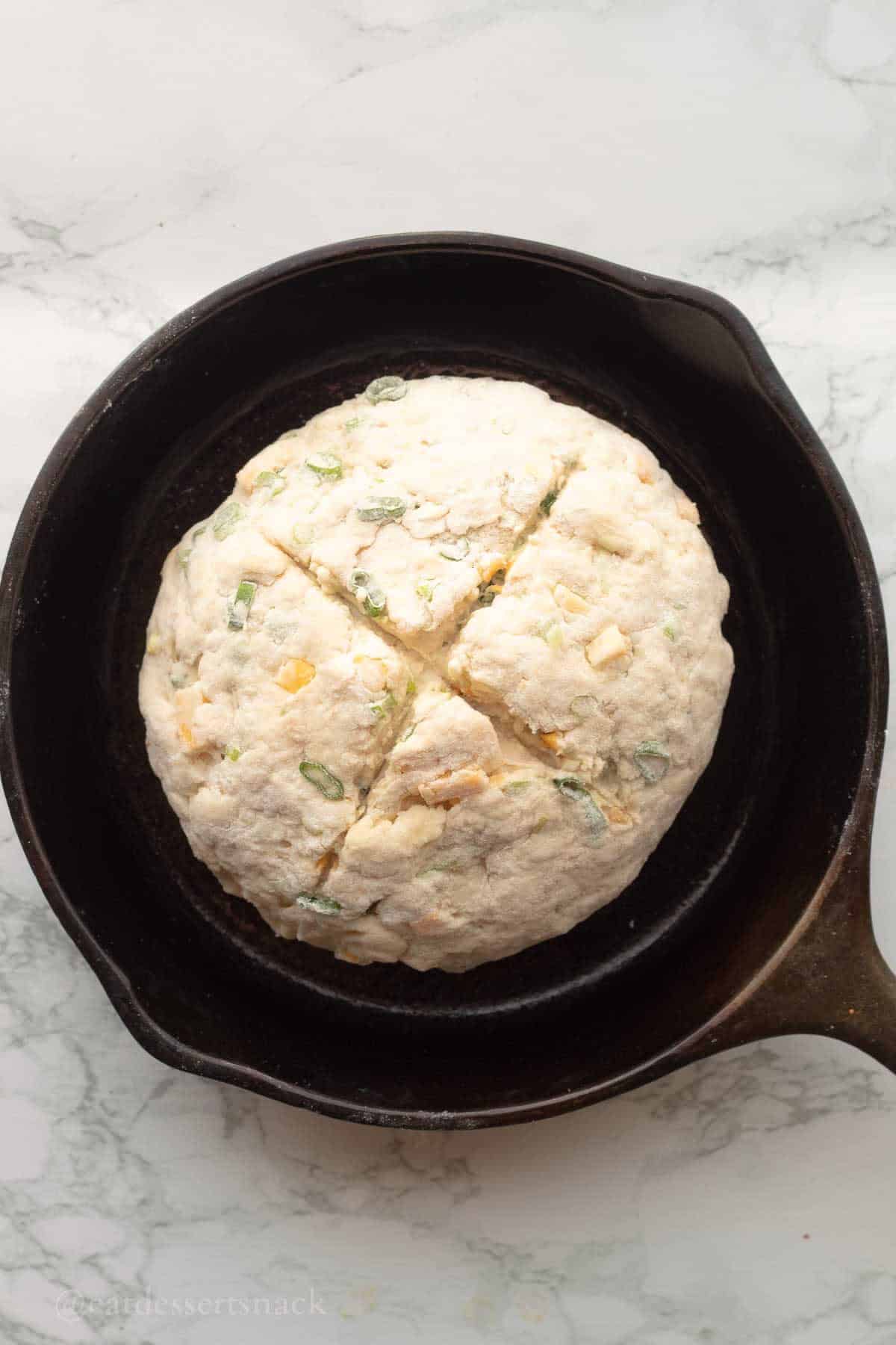 Cut raw irish soda bread in cast iron pan.
