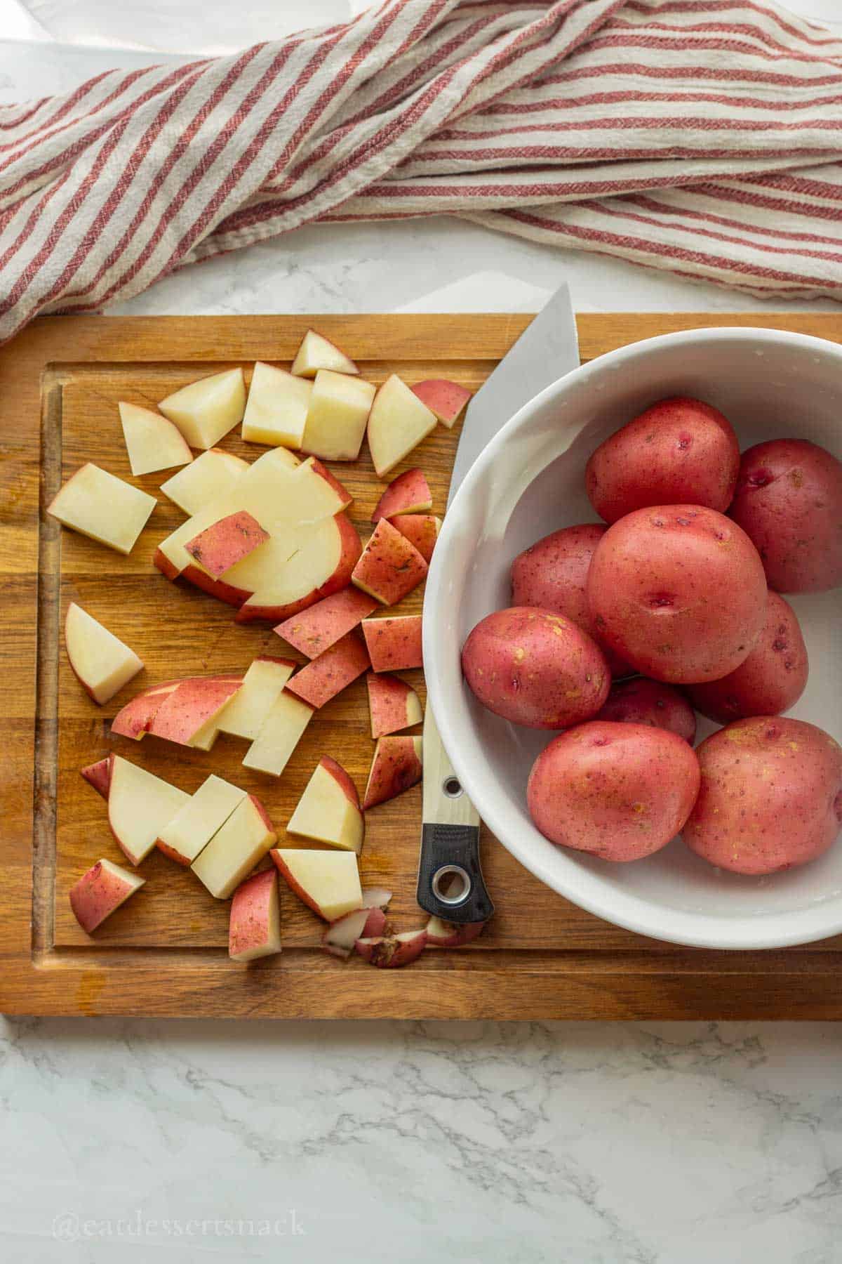 Slicing red potatoes on wood cutting board.