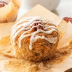 Icing drizzle over baked carrot banana muffin on brown paper.