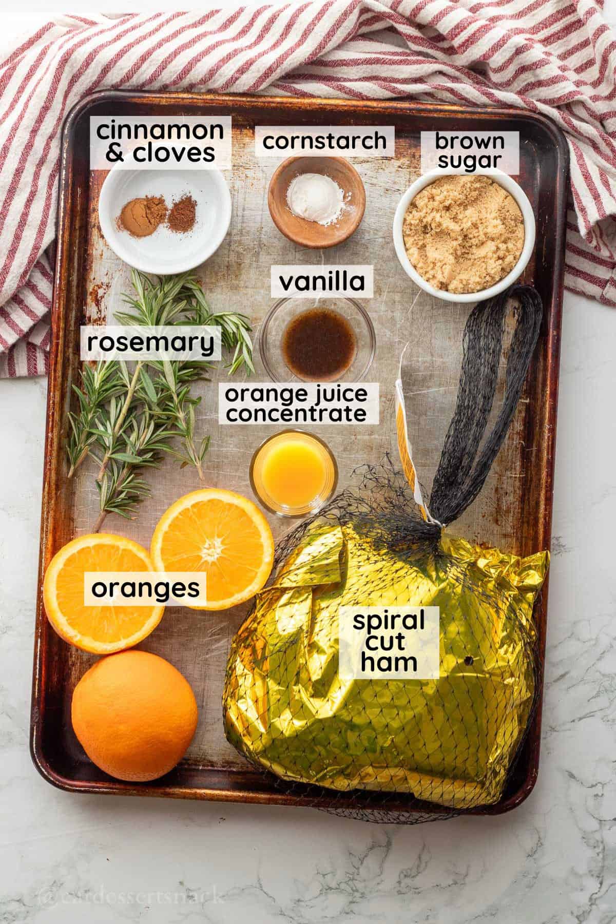 Labeled ingredients for orange ham glaze in glass bowls on metal pan.