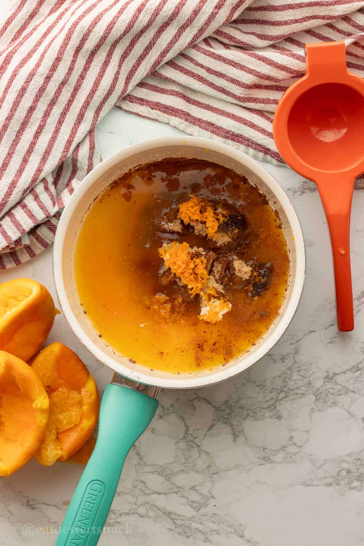 Orange zest, brown sugar, orange juice in metal cooking pan.