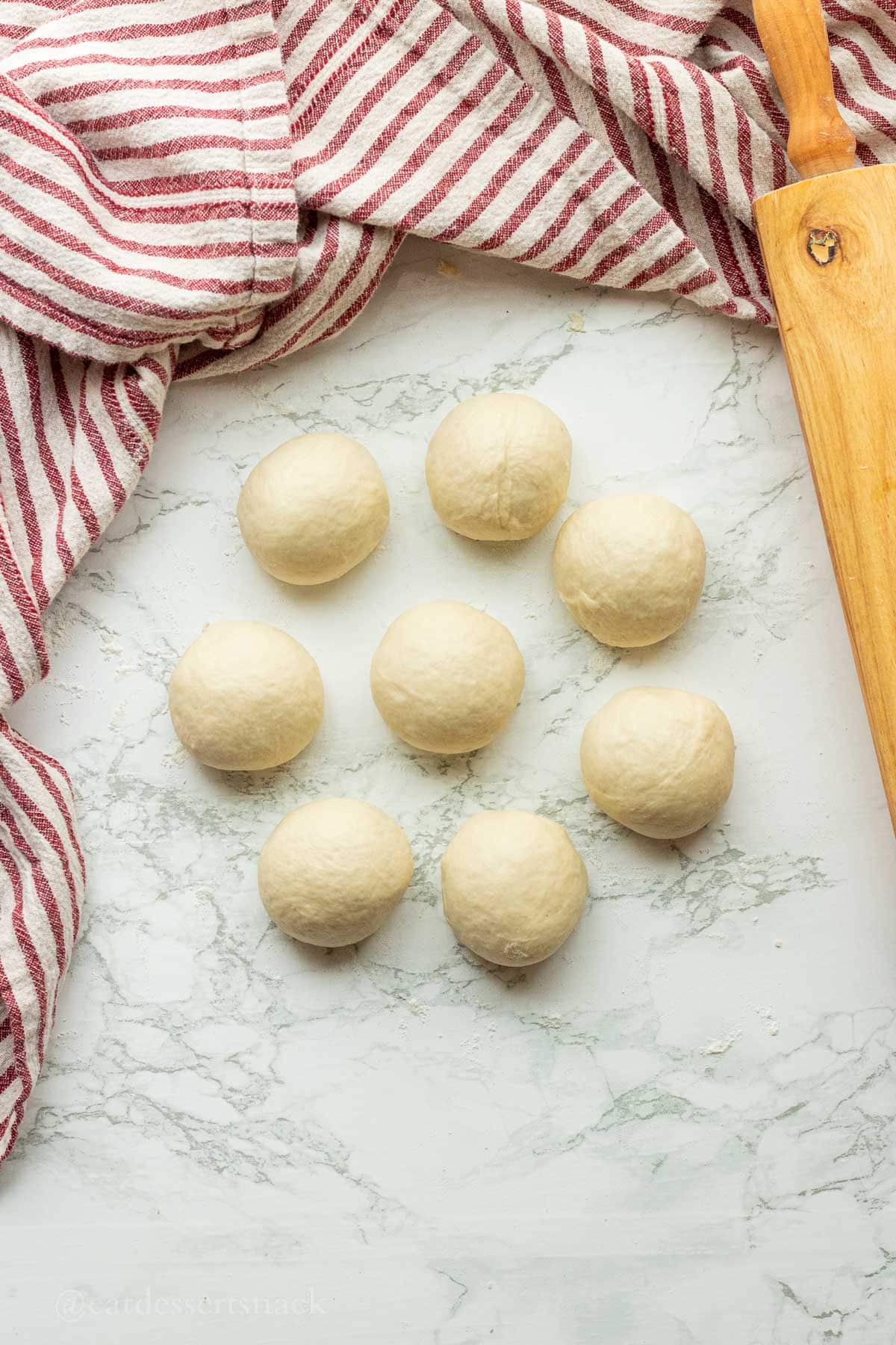 8 balls of tortilla dough on countertop.
