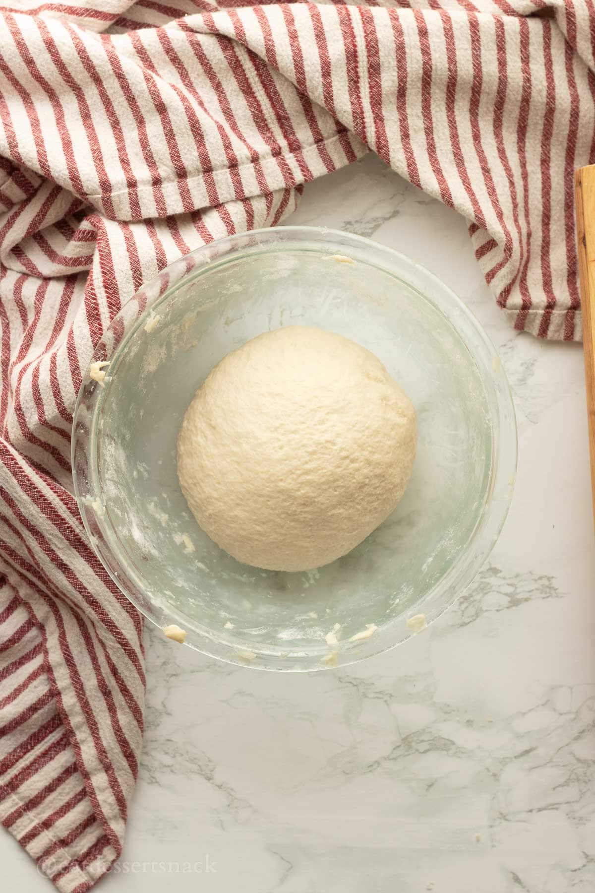 Ball of tortilla dough in glass bowl.