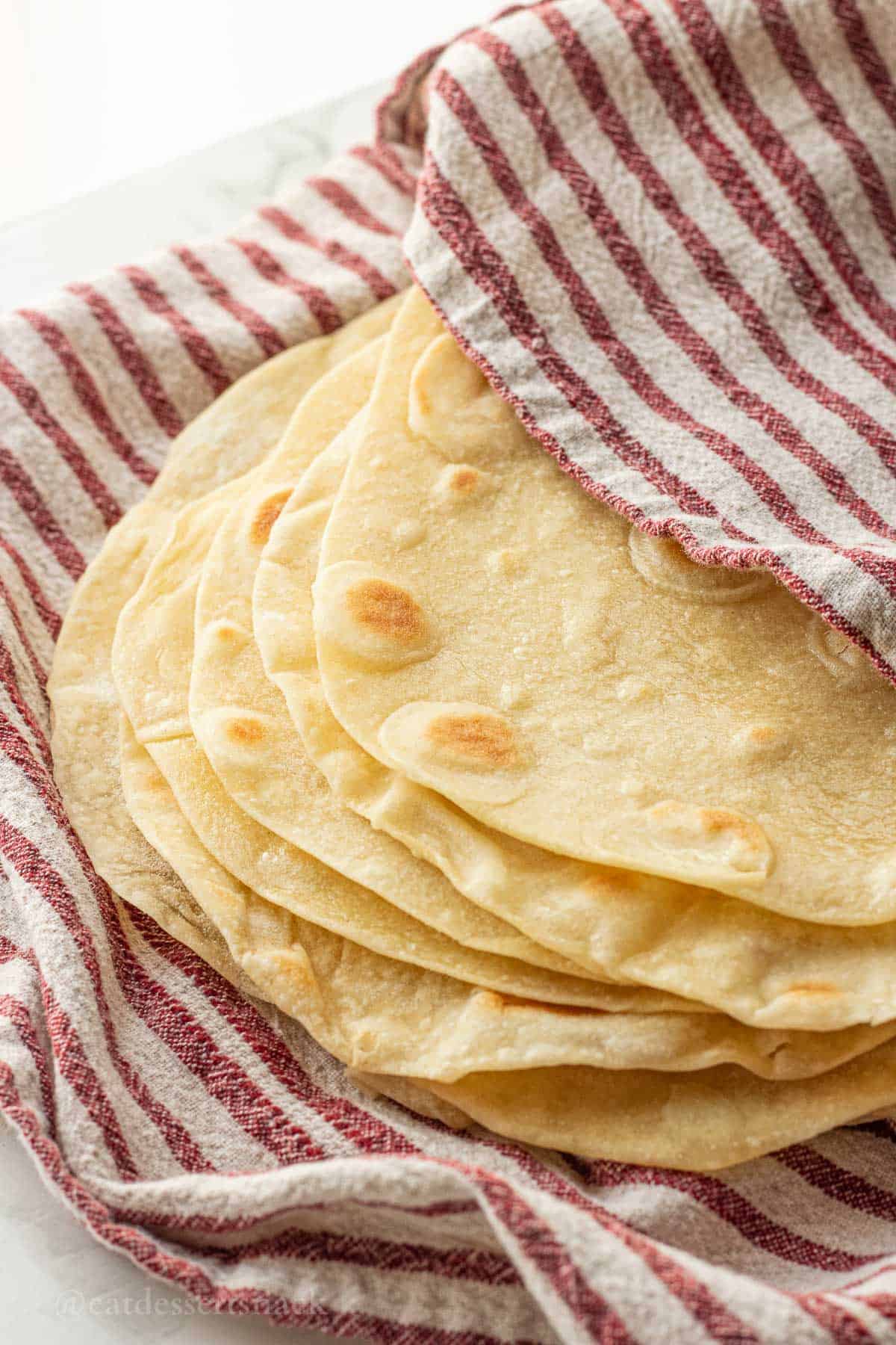 Stack of cooked tortillas in dish towel.
