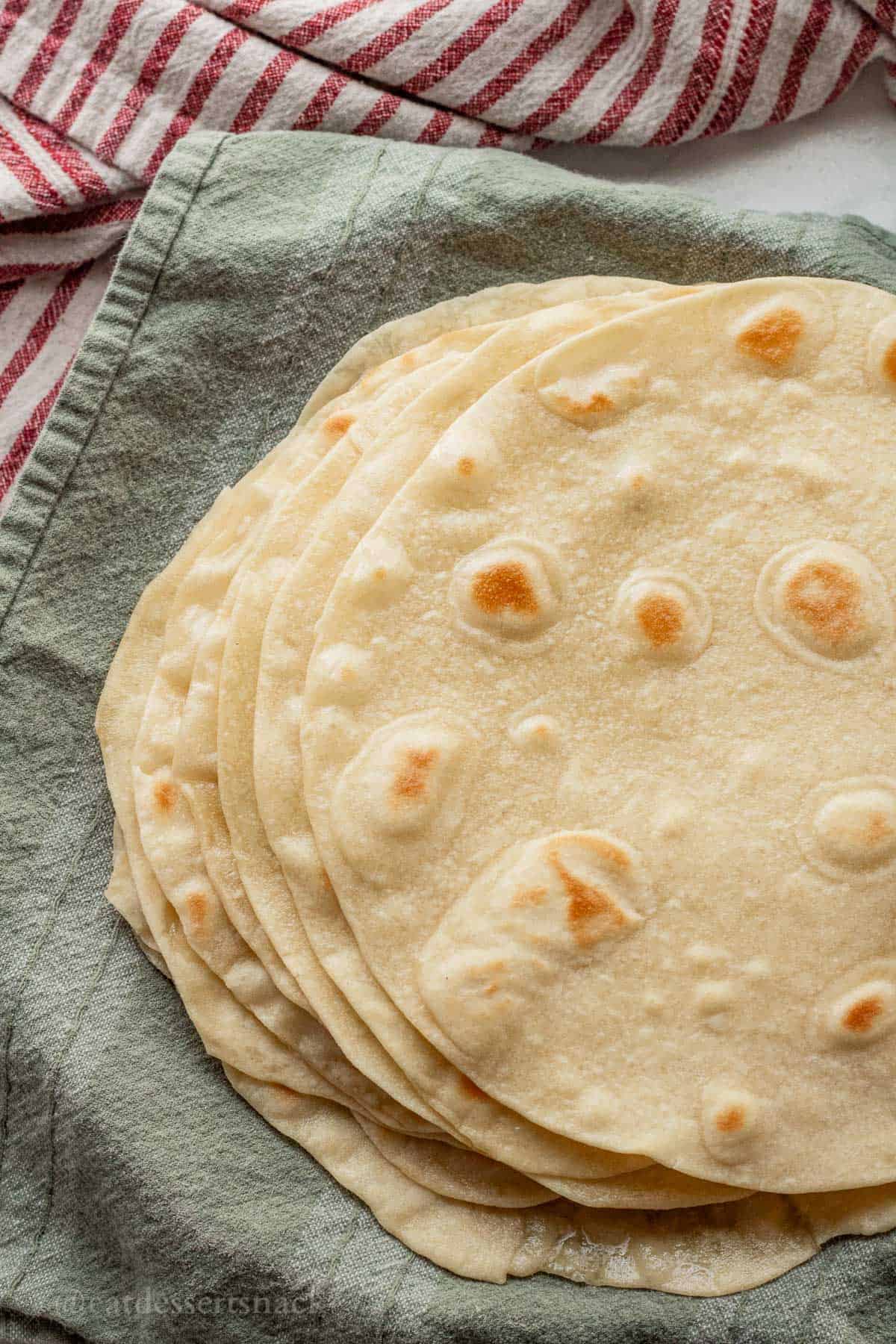 Cooked tortillas on dish towel.