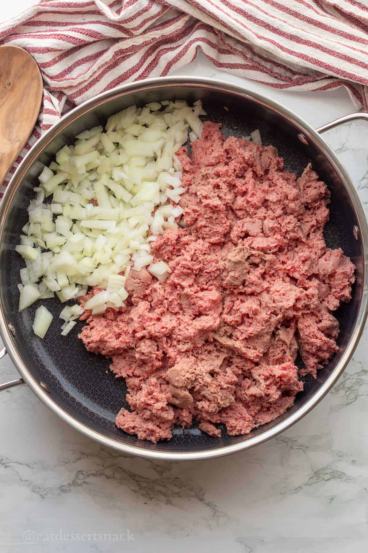 Raw ground turkey and onions in metal pan.