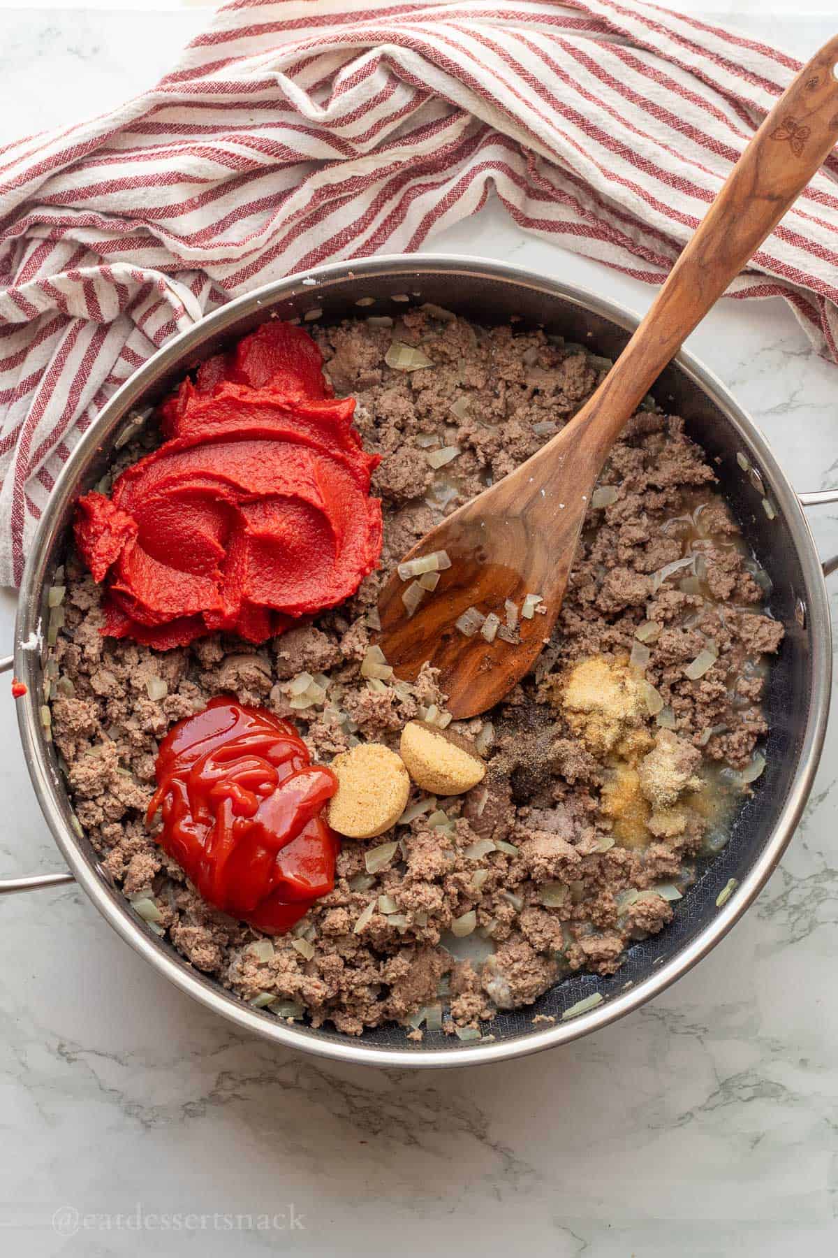 Tomato paste, ketchup, brown sugar, spices in ground turkey in metal pan.