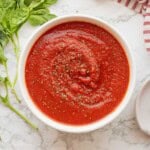 Pizza sauce in bowl with dried basil.