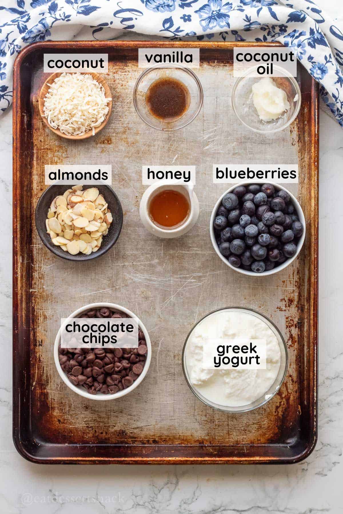 Labeled ingredients for frozen blueberries with yogurt in glass bowls on metal baking pan.