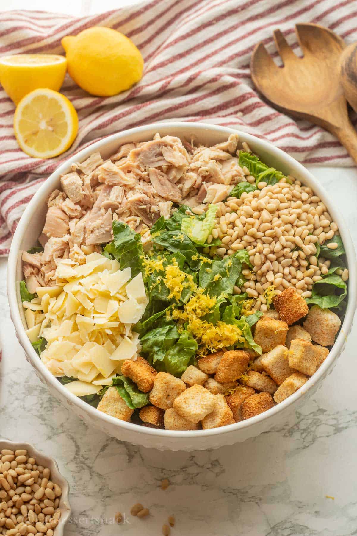 Lemon zest on chicken caesar salad in bowl.