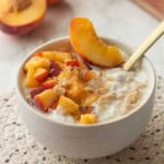 Bowl of cooked oatmeal with peaches and brown sugar.