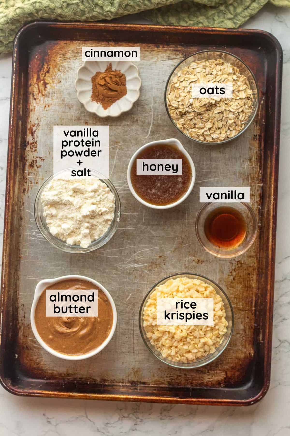 Labeled ingredients for protein cinnamon balls on metal baking sheet.