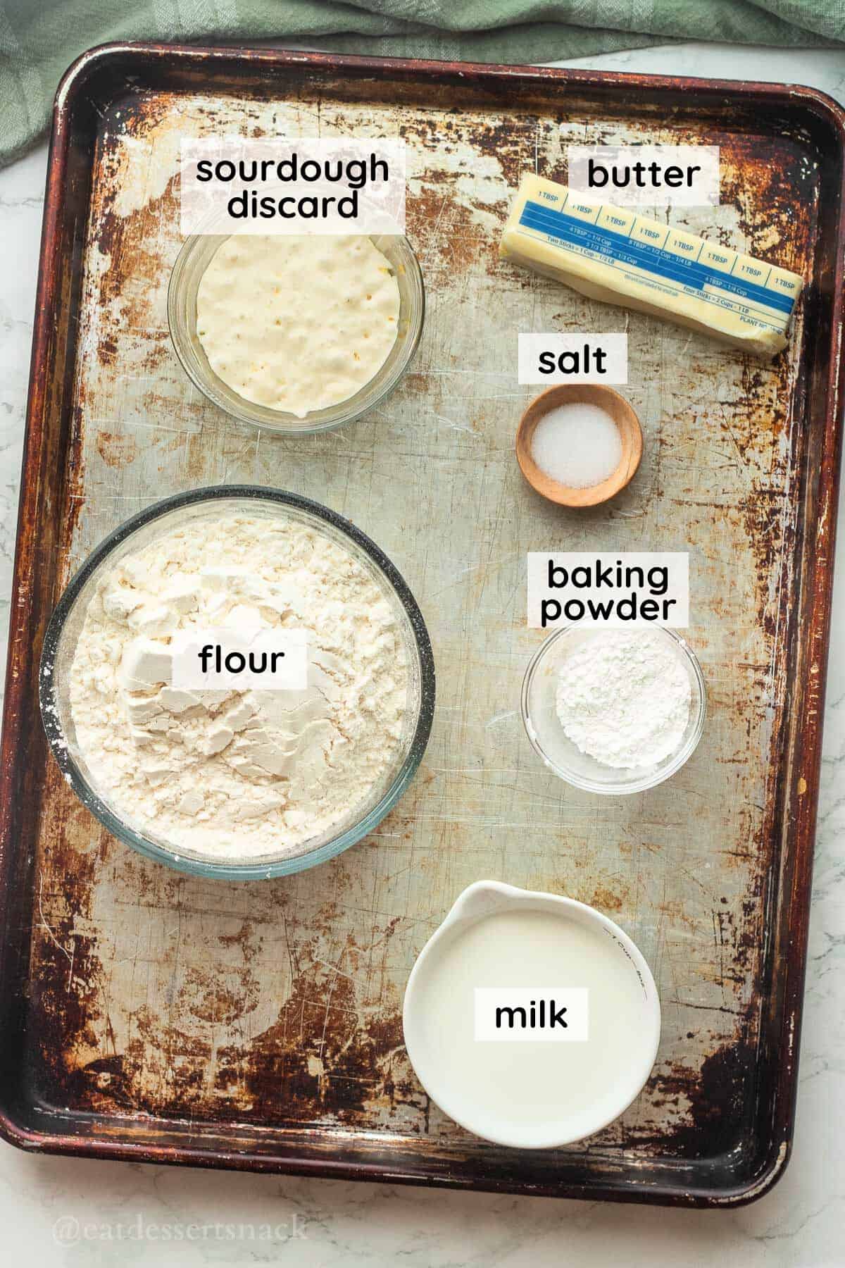 Labeled ingredients in dishes for sourdough biscuits on metal baking sheet.