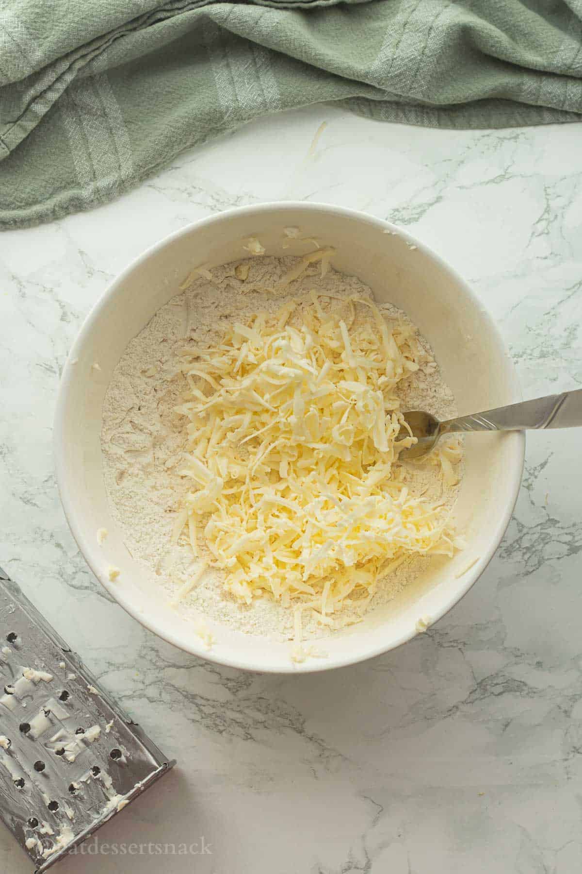 Grated butter in bowl of flour with fork.