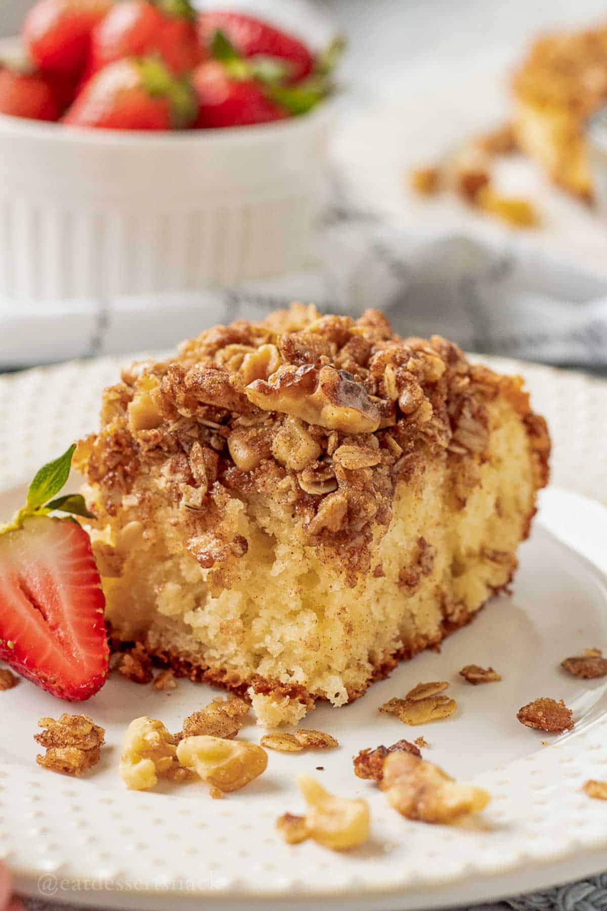 Slice of baked coffee cake with strawberry on plate.