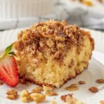 Slice of baked coffee cake with strawberry on plate.