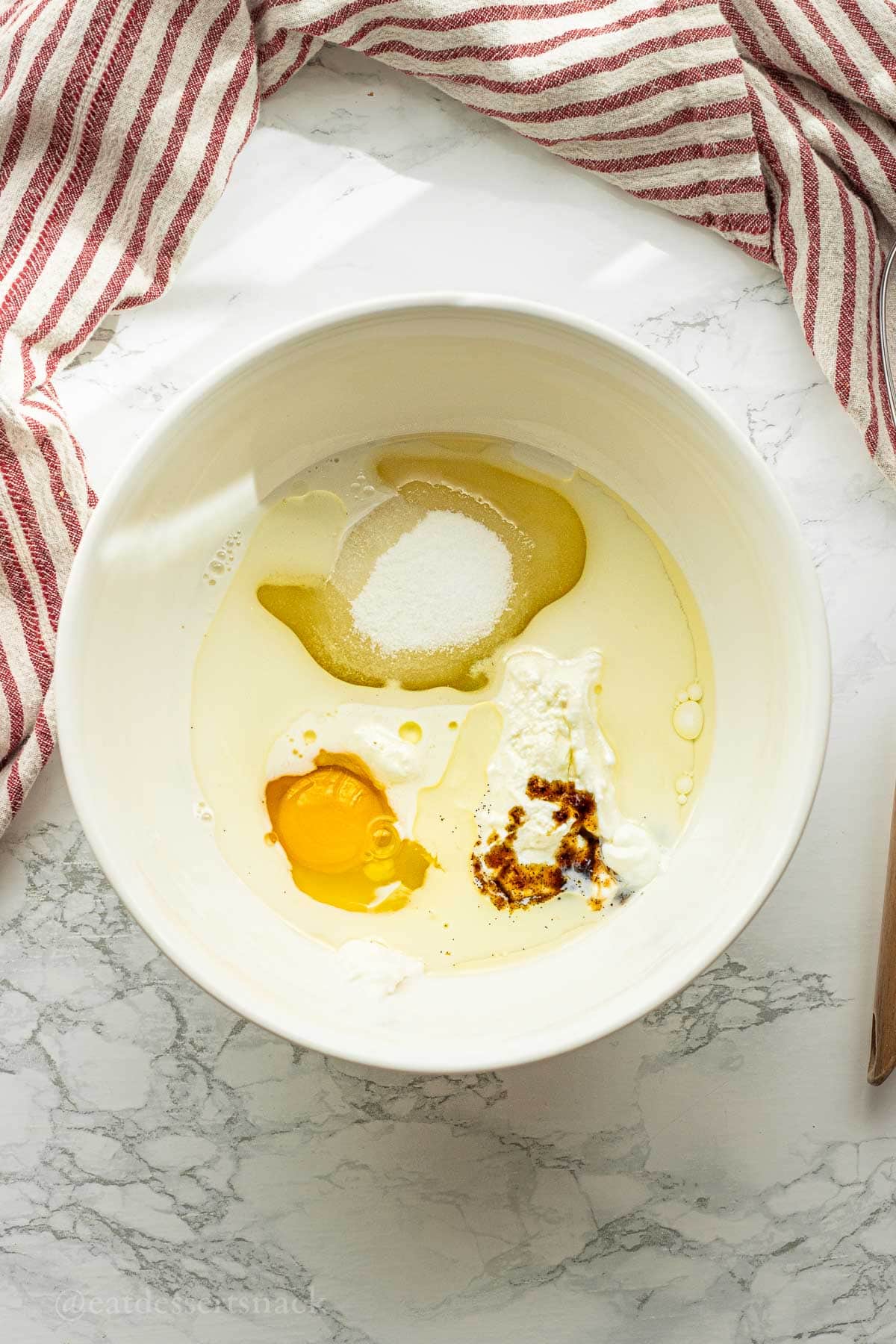 Sugar, egg, vanilla, greek yogurt, oil, and milk in bowl.
