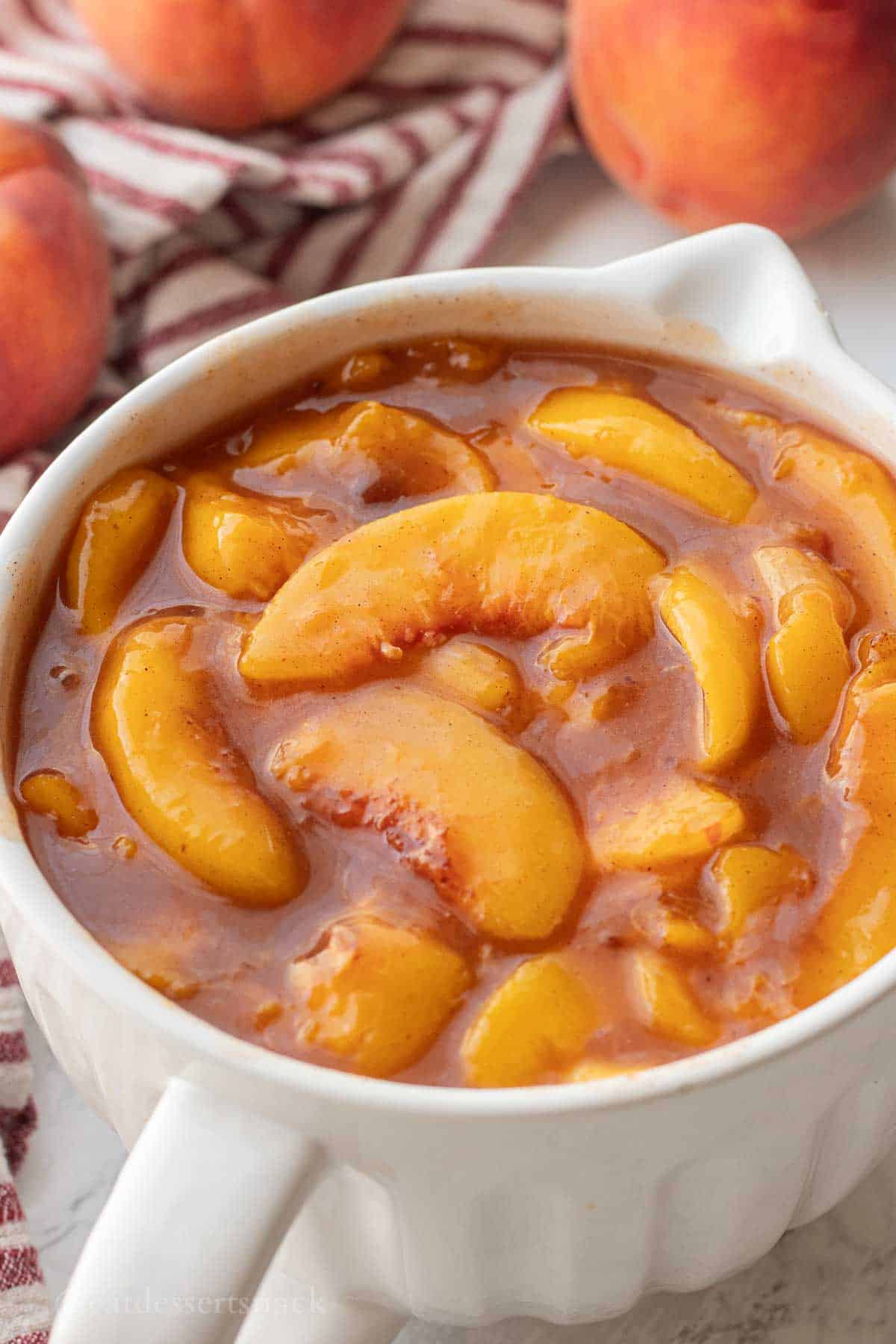 Cooked peach pie filling in white bowl.