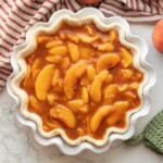 Cooked peach pie filling in raw pie shell.