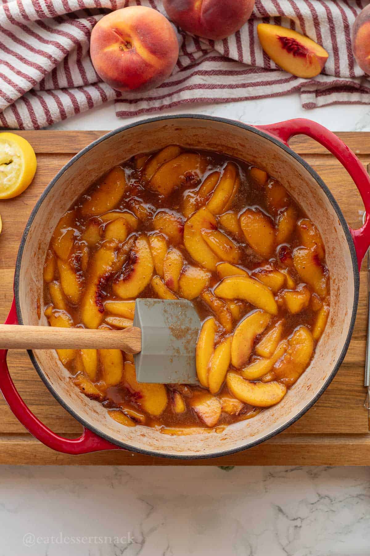 Cooked peach pie filling in pan with rubber spatula.