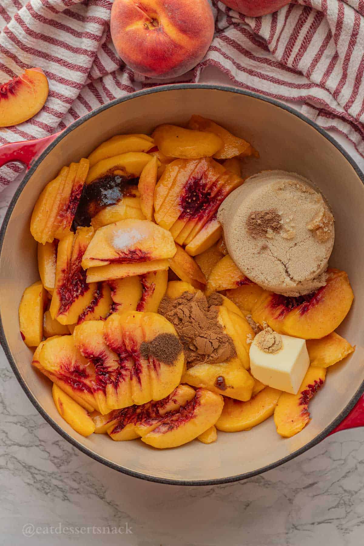 Raw peach pie filling ingredients in red pan.