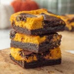 Stacked baked pumpkin cheesecake brownies.