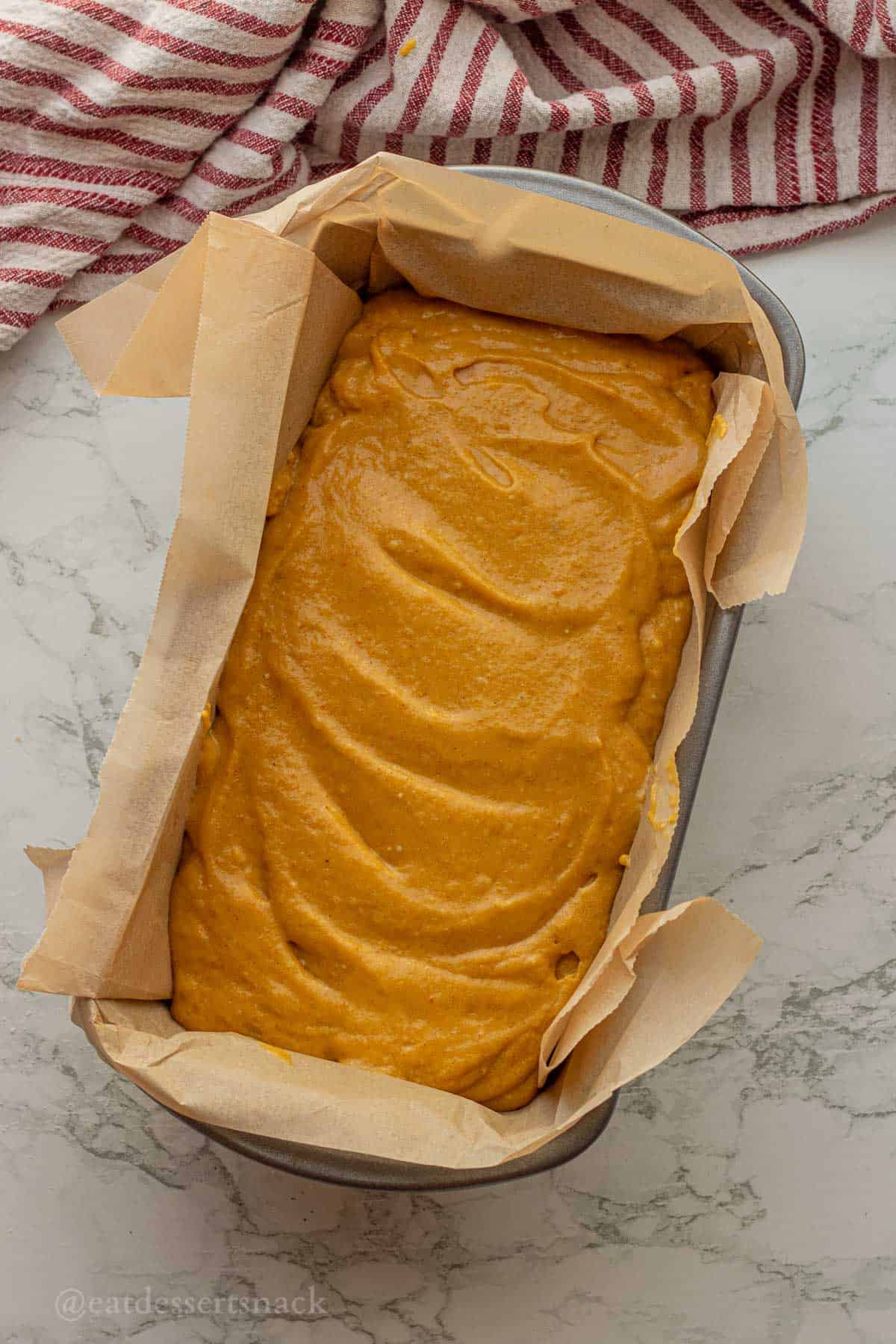 Raw pumpkin bread batter in parchment lined bread pan.