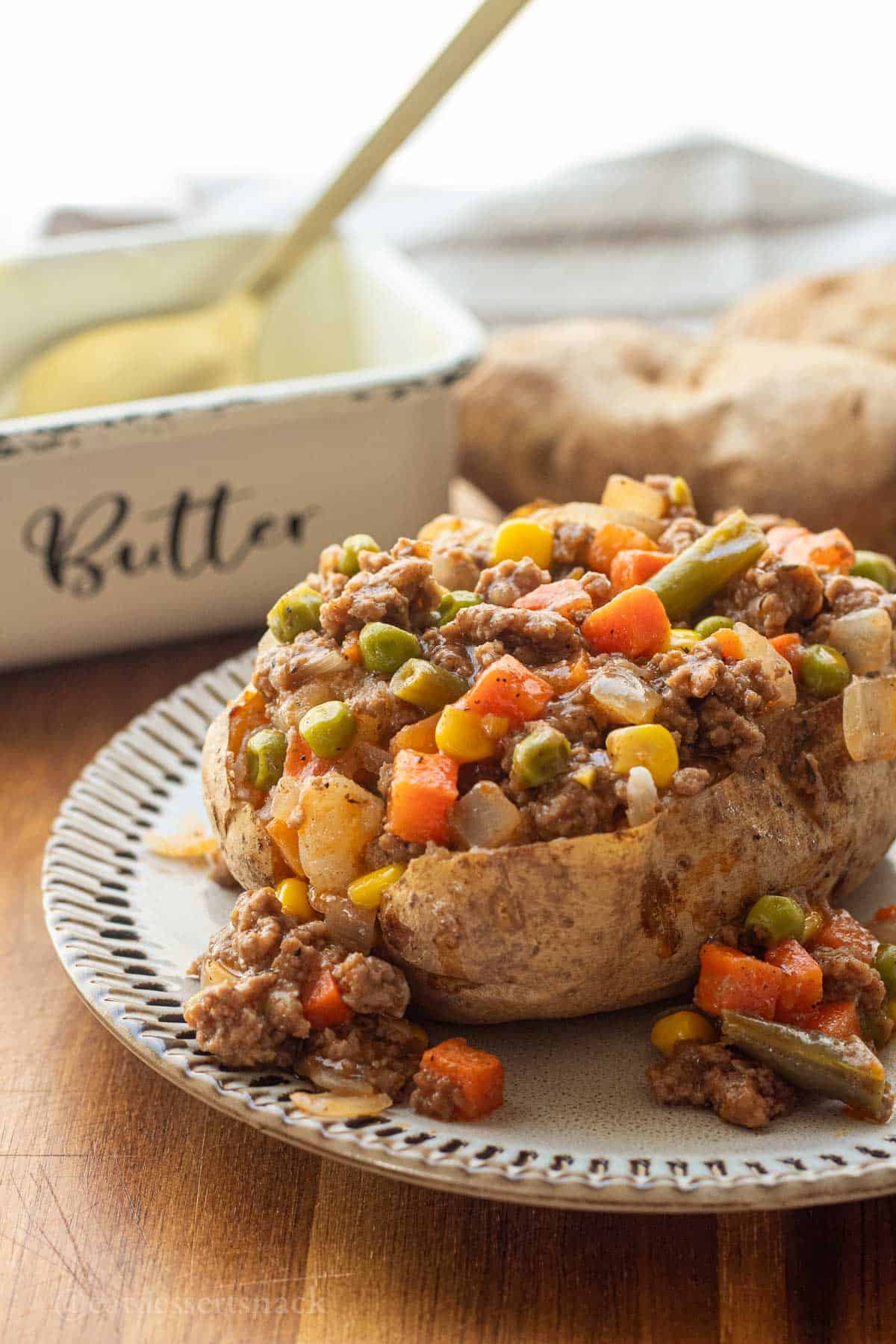 Shepherd's pie filling in baked potato on plate.