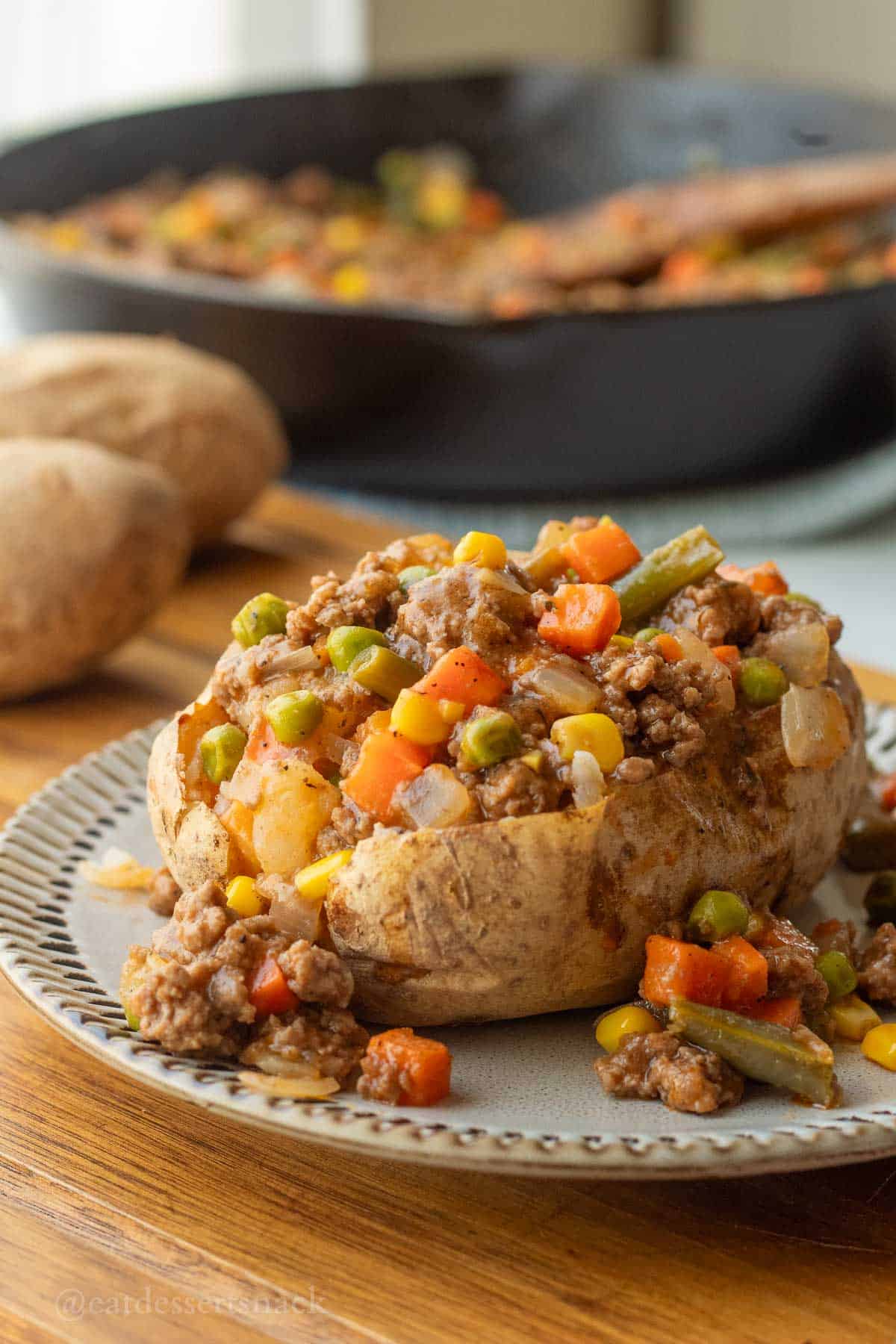 Shepherd's pie filling in baked potato on plate.
