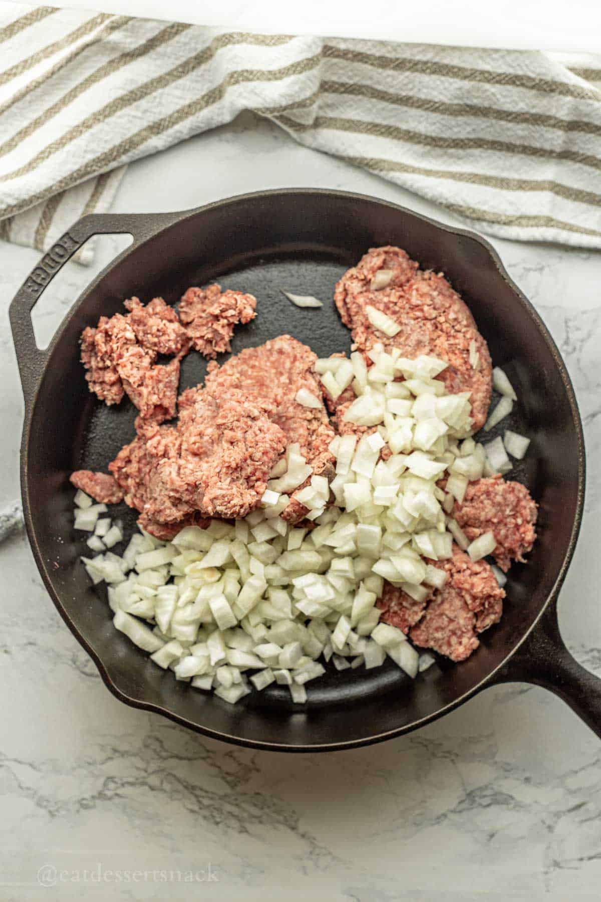 Raw meat and onions in pan.