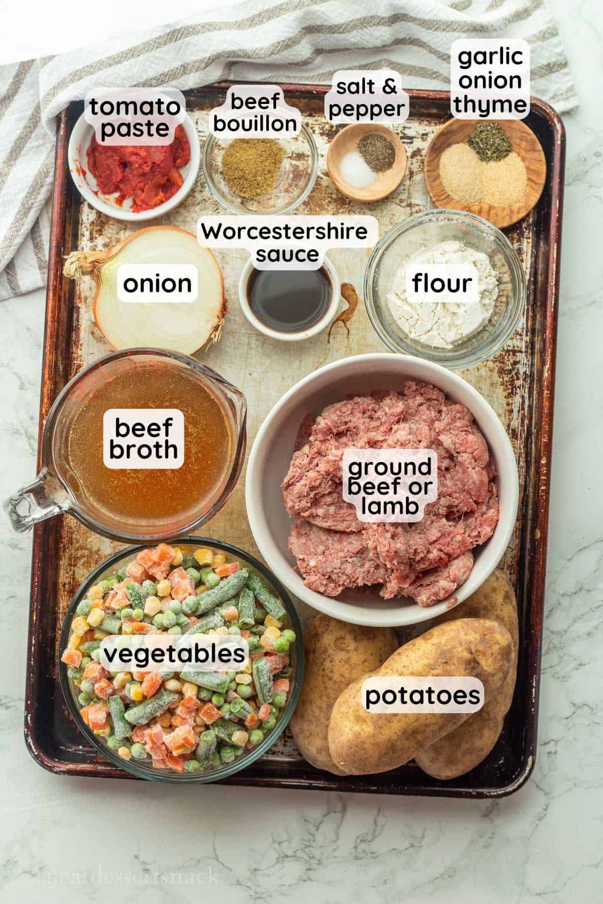 Labeled ingredients for shepherds pie baked potatoes on metal pan.