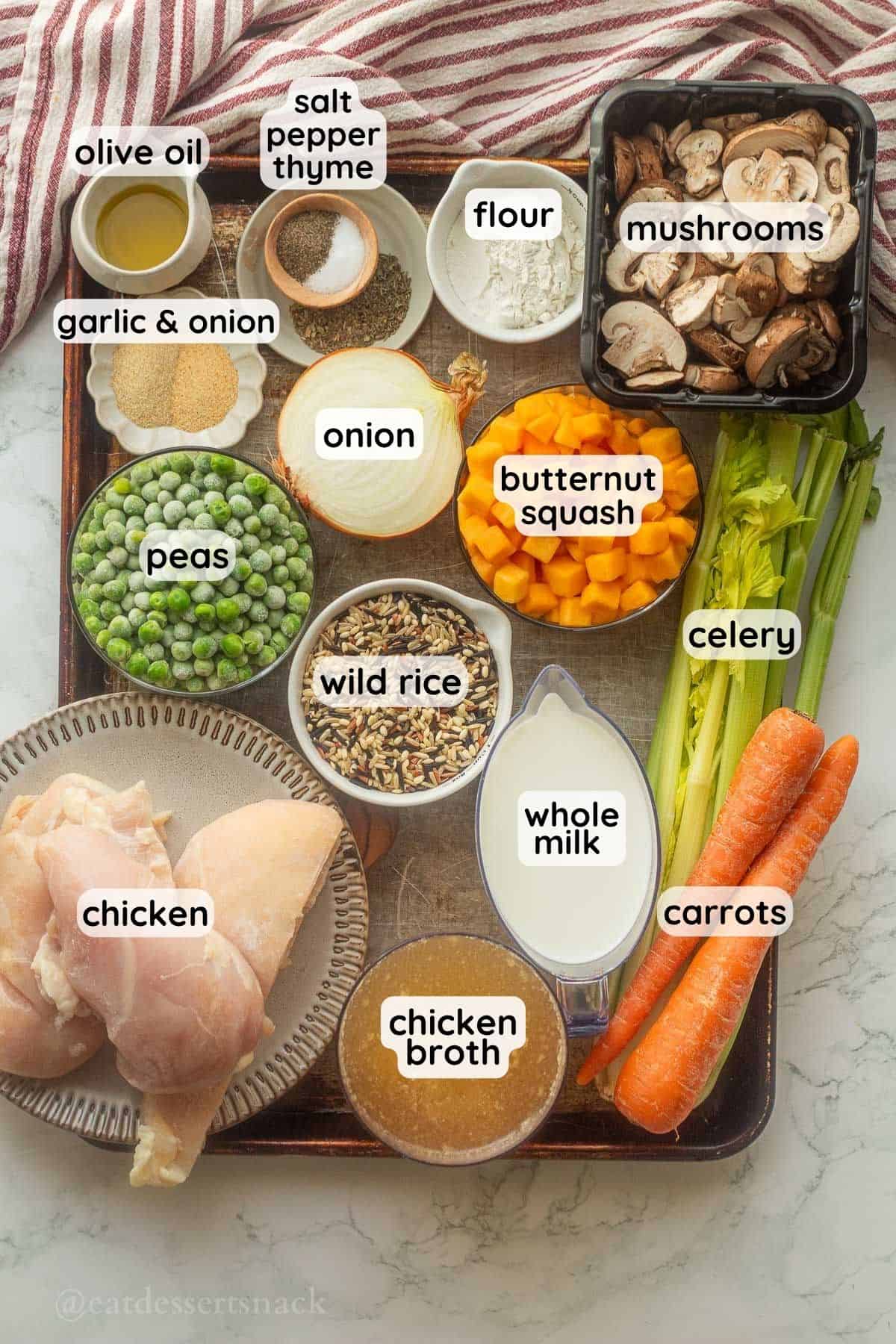 Labeled ingredients for creamy chicken and wild rice soup in bowls on metal pan.