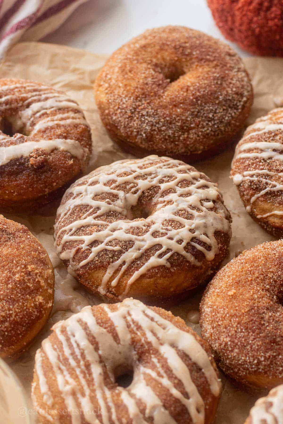 Baked glazed apple cider donuts on parchment paper.