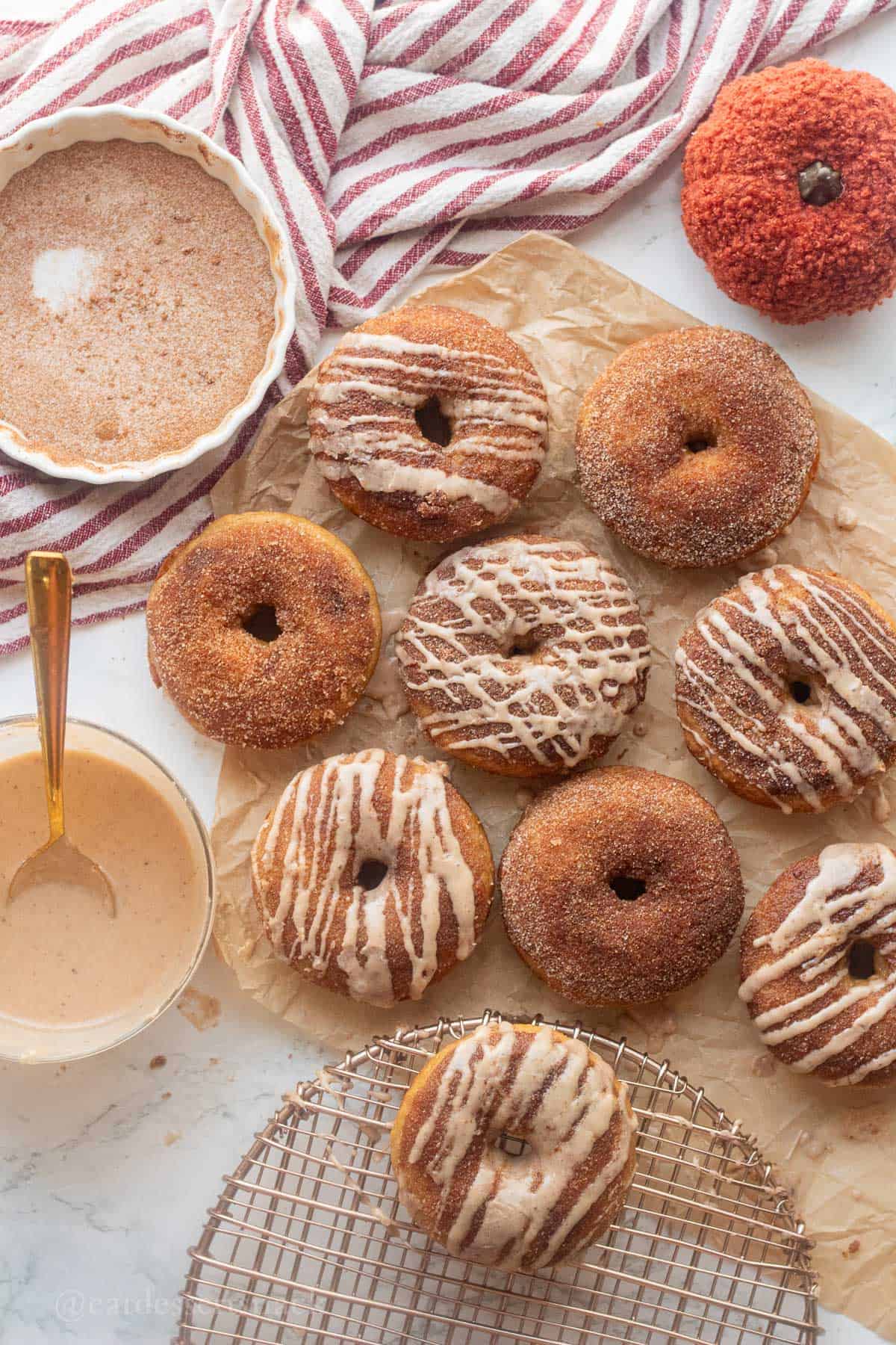 Baked apple cider donut on parchment paper glazed and sugared.