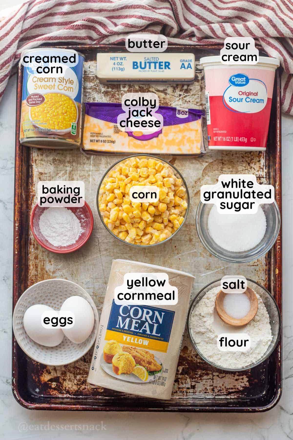 Labeled ingredients for slow cooker cornbread pudding on metal pan.