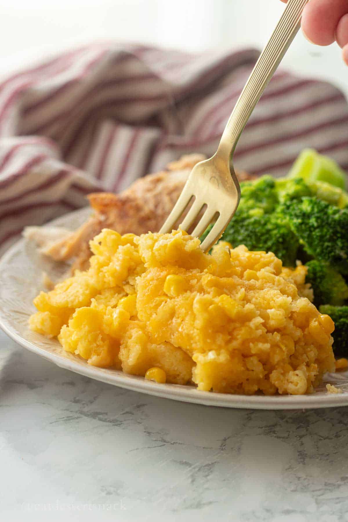 Cooked corn pudding with broccoli and meat on a plate with fork.