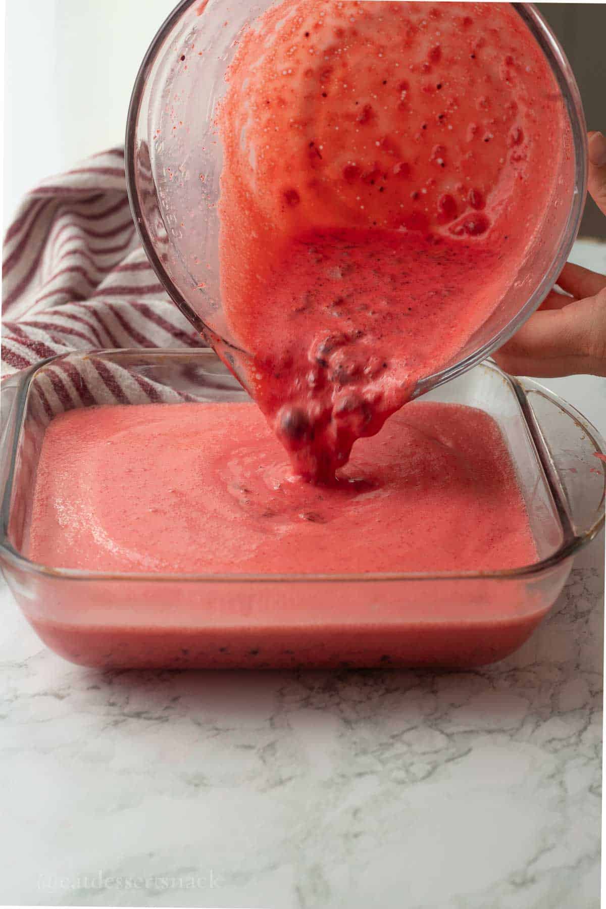 Pouring jello mixture into 9x9 inch pan.