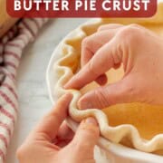 Fingers crimping pie crust in pan.