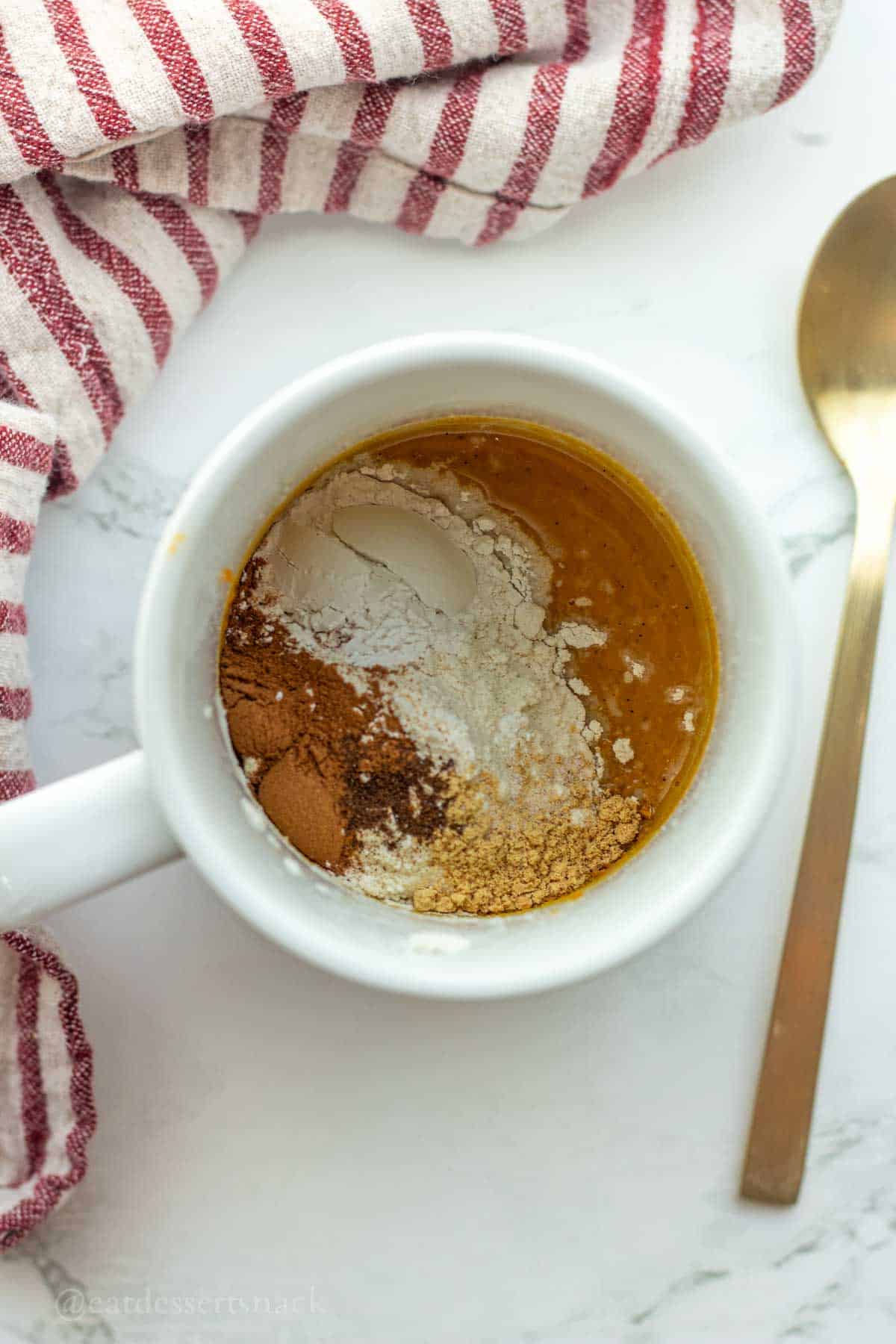 Dry ingredients on top of wet ingredients in mug.