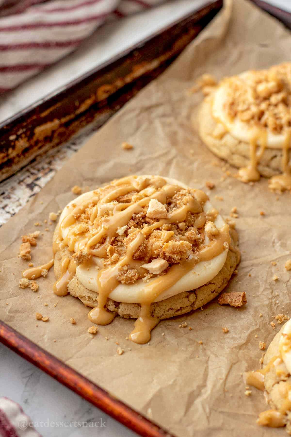 Baked caramel apple cookie on pan with caramel drizzle.