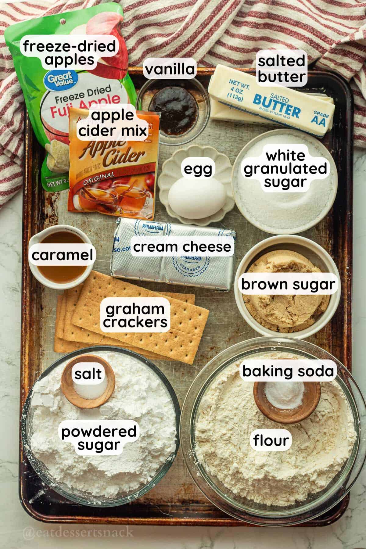 Labeled ingredients in glass bowls for caramel apple cookies.