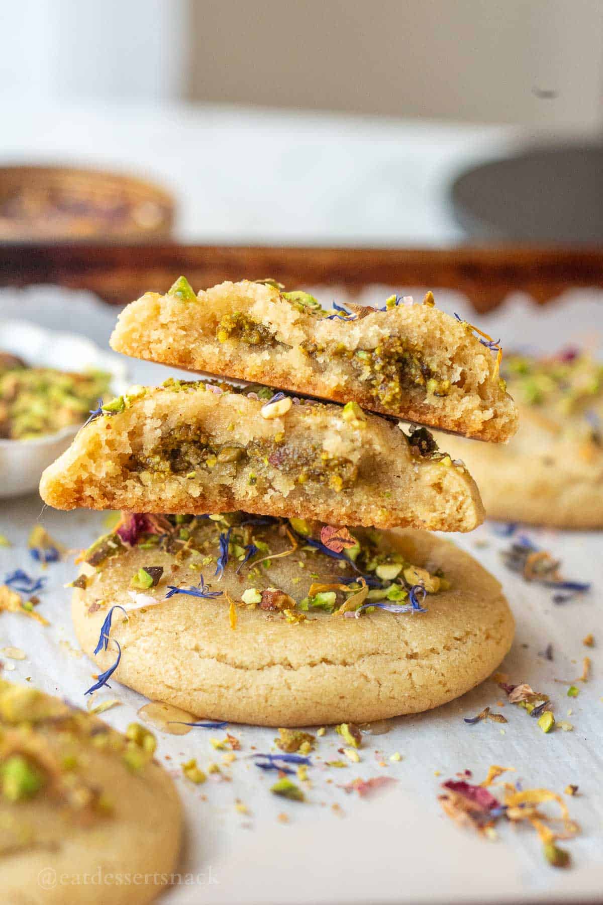 Halved baklava cookies on baking sheet stacked.