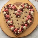 Frosted heart shaped cookie cake on wood platter.