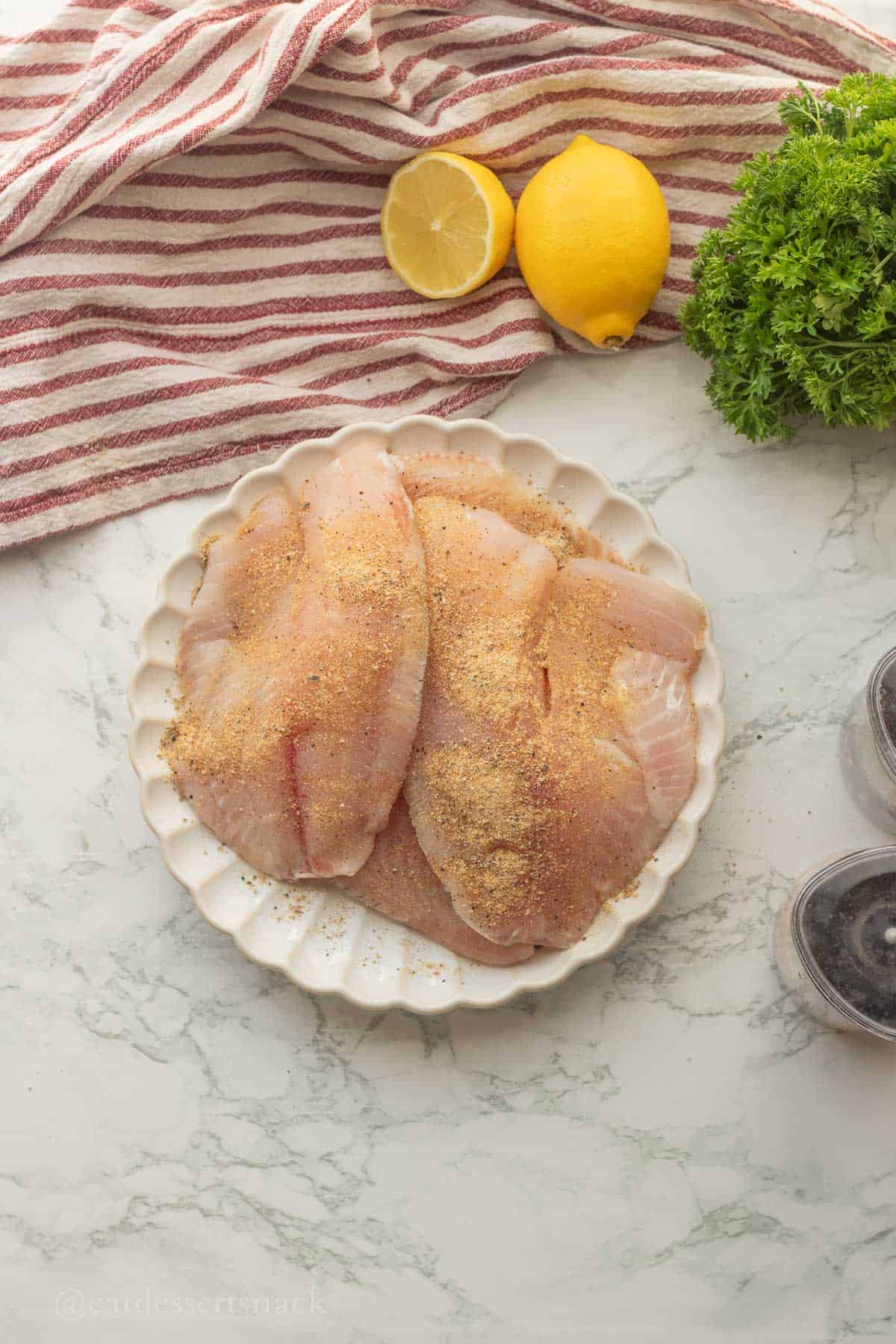 Raw tilapia seasoned on plate.