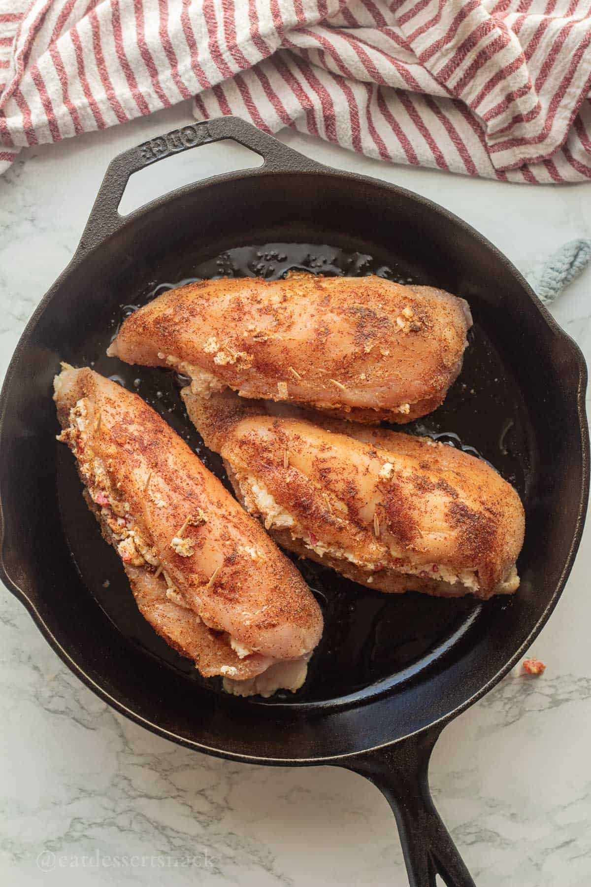 Raw chicken breasts in frying pan.