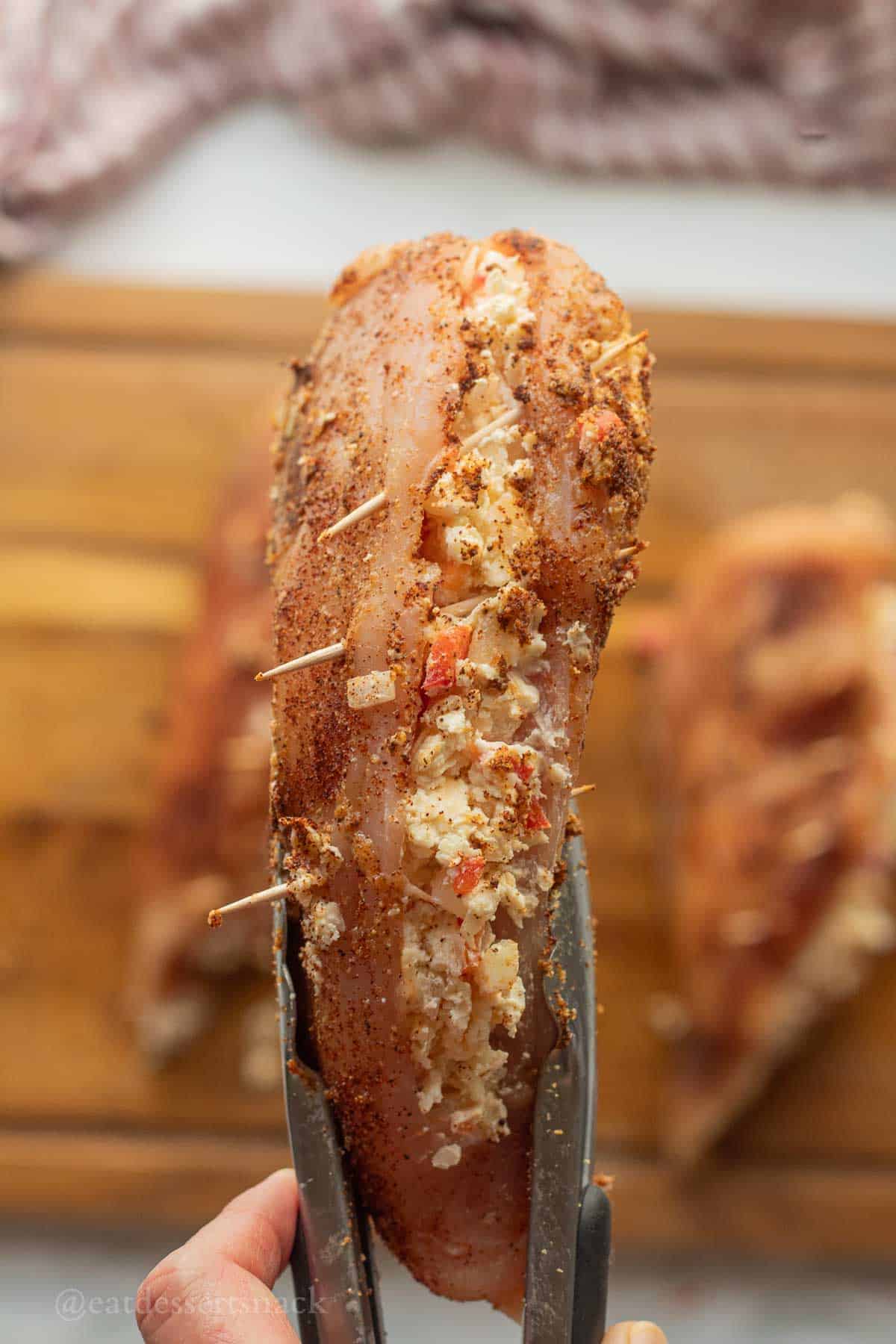 Raw stuffed chicken breast with toothpicks inserted.