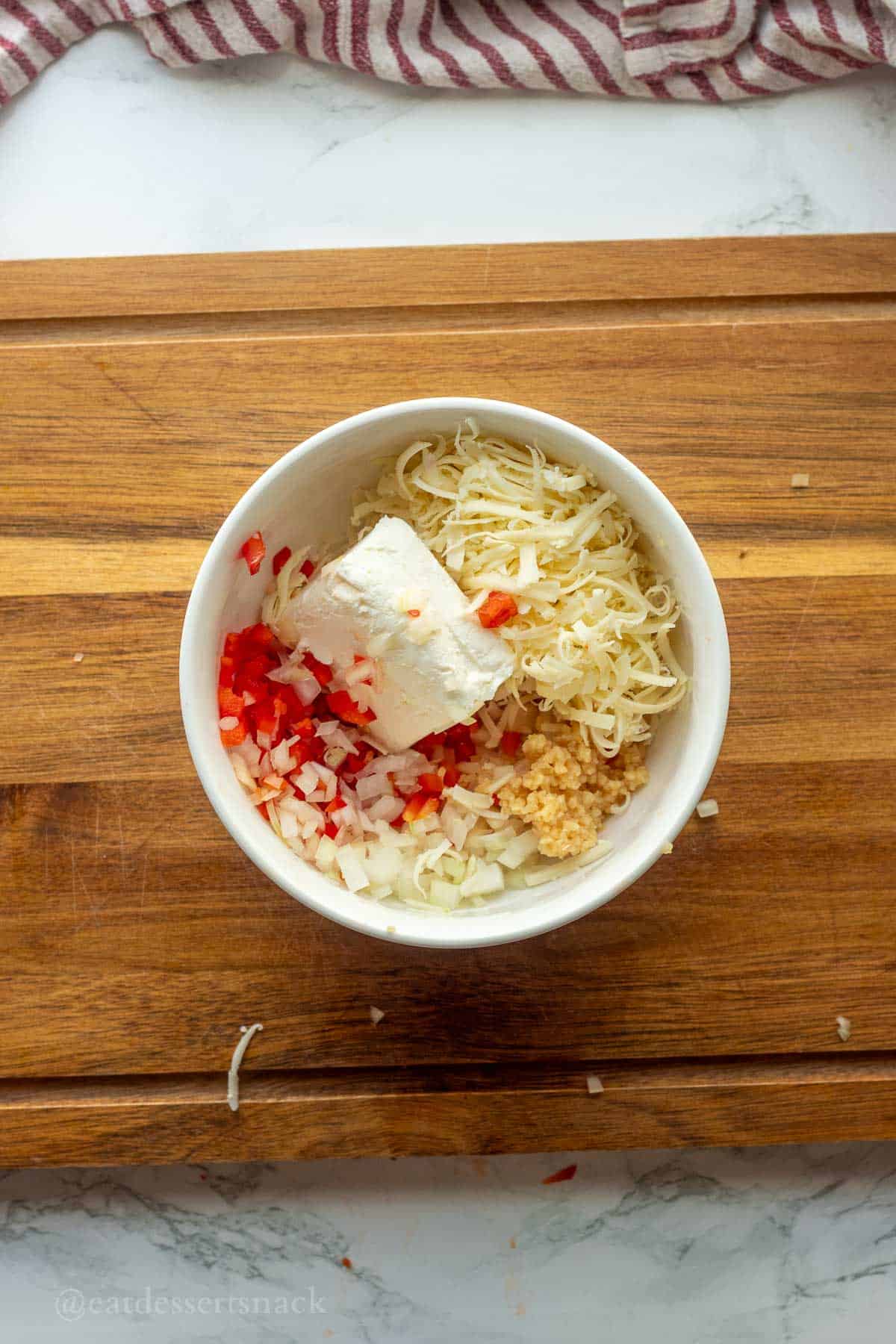 Cheese, peppers, onions, and garlic in bowl.