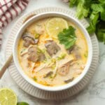 Bowl of Thai coconut chicken soup with lime and cilantro.