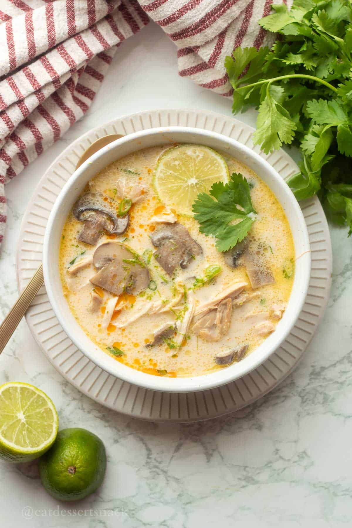 Bowl of Thai coconut chicken soup with lime and cilantro.